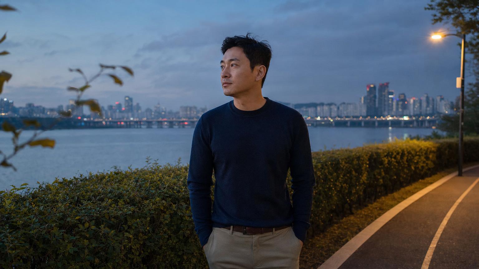 Third patient case (Korean man in his early forties) at month 3 after Korean micro-cannula liposuction of the flanks and submental zone showing settled contour with restored waistline definition and a sharper jawline, photographed in a charcoal and brushed steel urban gym setting in a fitted athletic shirt with confident neutral posture