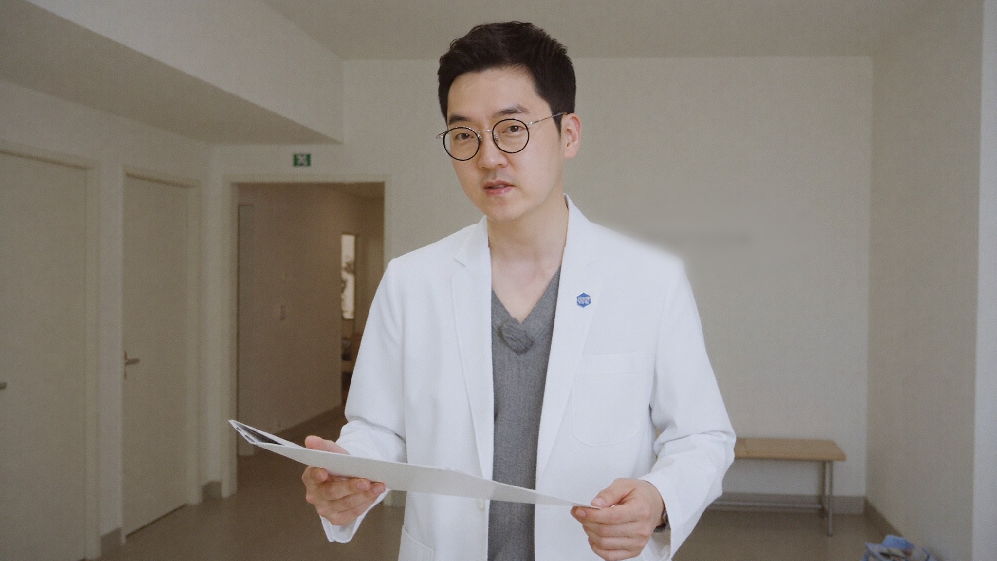 Dr. Jung Min Su, co-director at Link Plastic Surgery, reviewing notes in the clinic corridor.